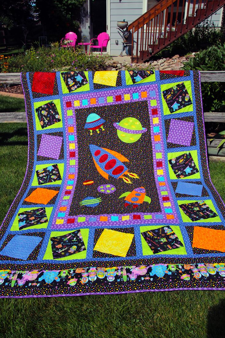 a patchwork quilt on the grass in front of a house