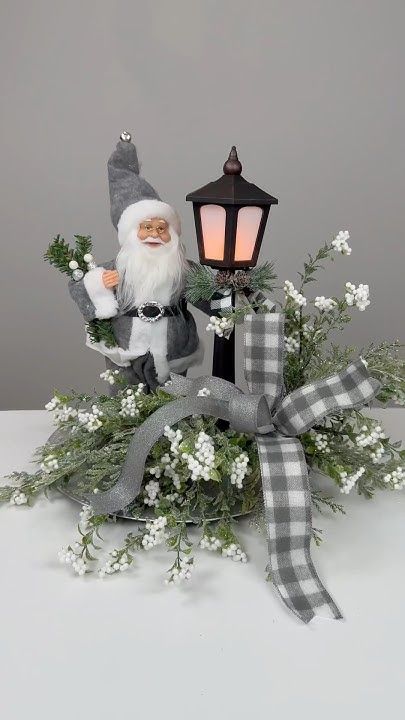 a christmas decoration with a santa clause holding a lantern and flowers in front of it