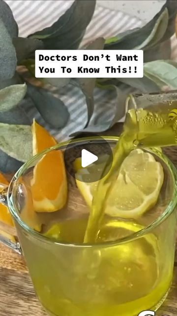 a glass cup filled with liquid and lemon wedges on top of a wooden table