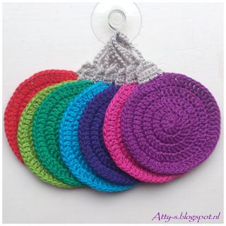 four crocheted coasters in different colors on a white background with a metal hook