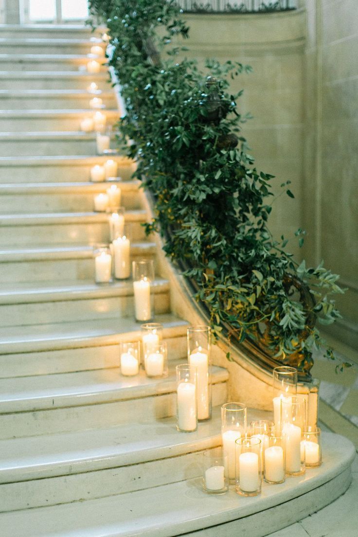 candles are lined up on the steps in front of a planter with greenery