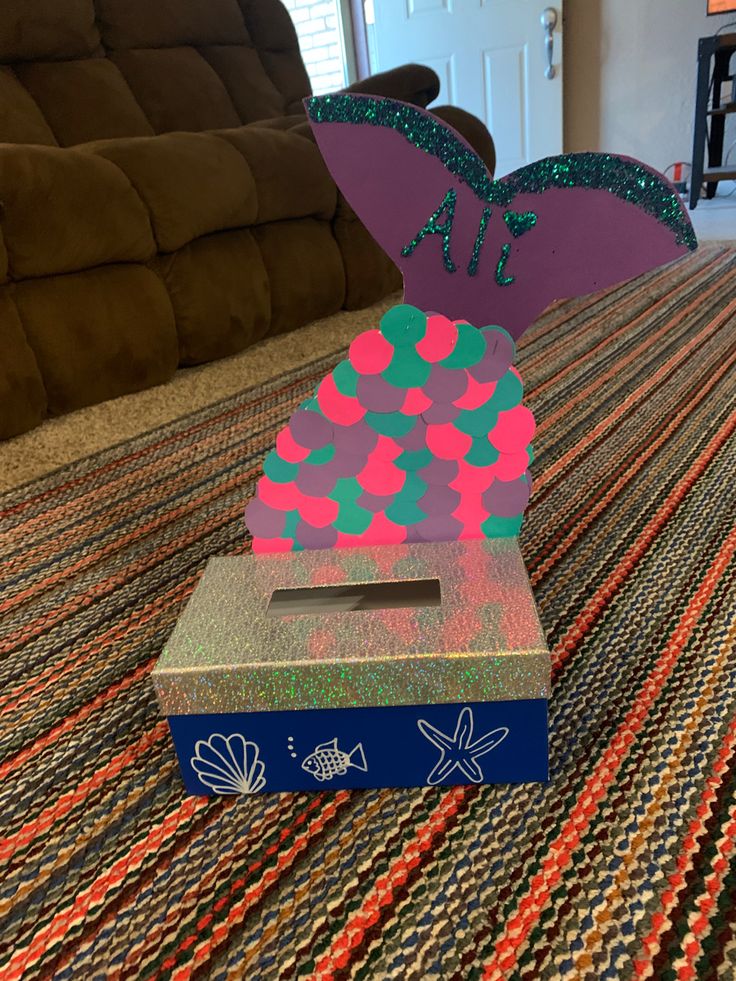 a purple and green award sitting on top of a carpeted floor next to a couch