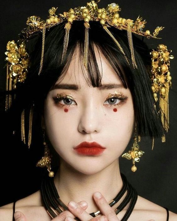 a woman with black hair and gold jewelry on her head is looking at the camera