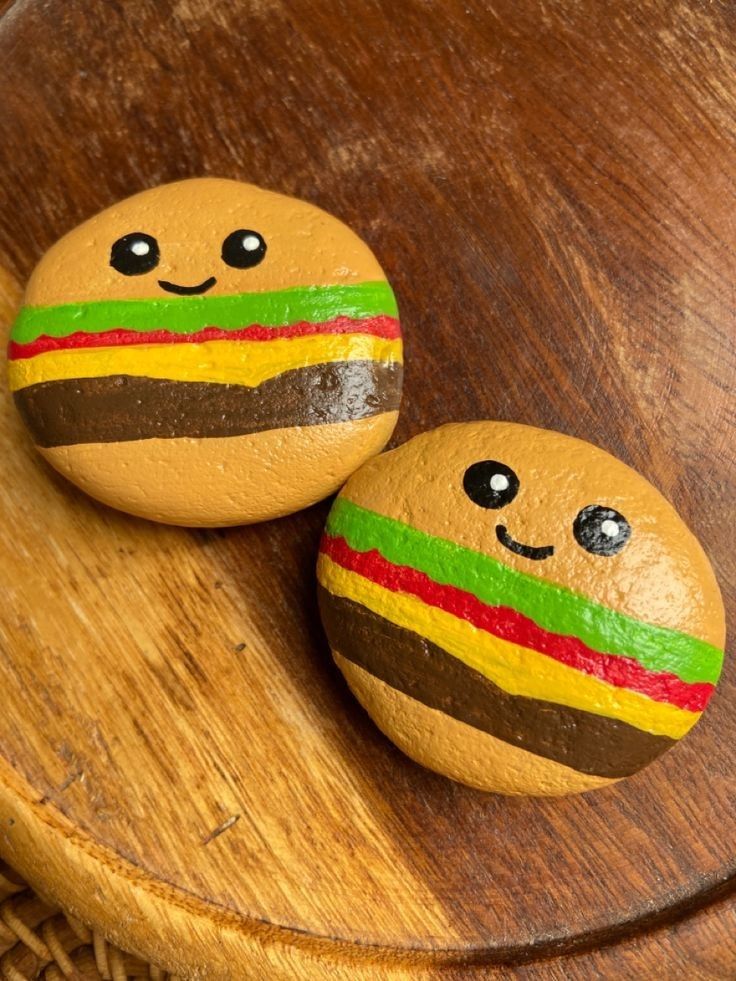 two painted rocks sitting on top of a wooden table