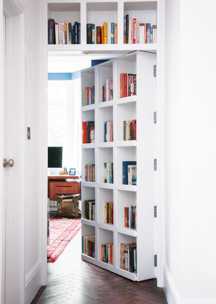 a white book shelf filled with lots of books in a living room next to a door