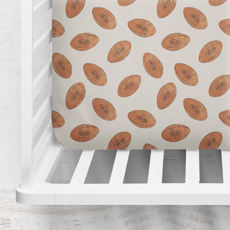 a white crib with an orange football print on it