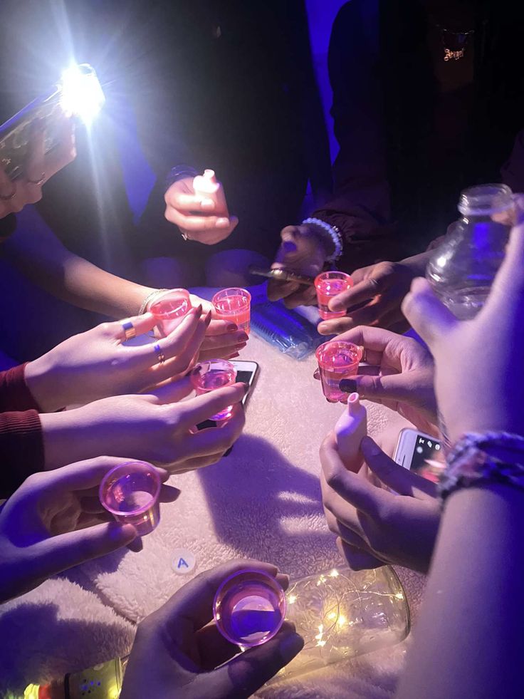 several people are sitting at a table with their cell phones in front of them and one person is holding a lighter