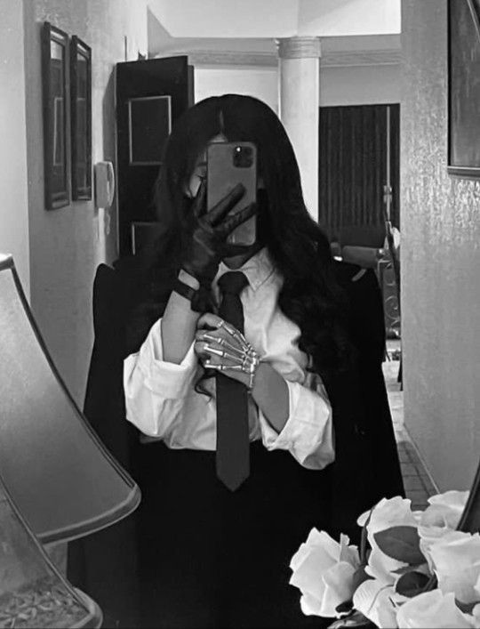 a woman taking a selfie in front of a mirror wearing a suit and tie