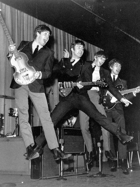 the beatles performing on stage with their guitars