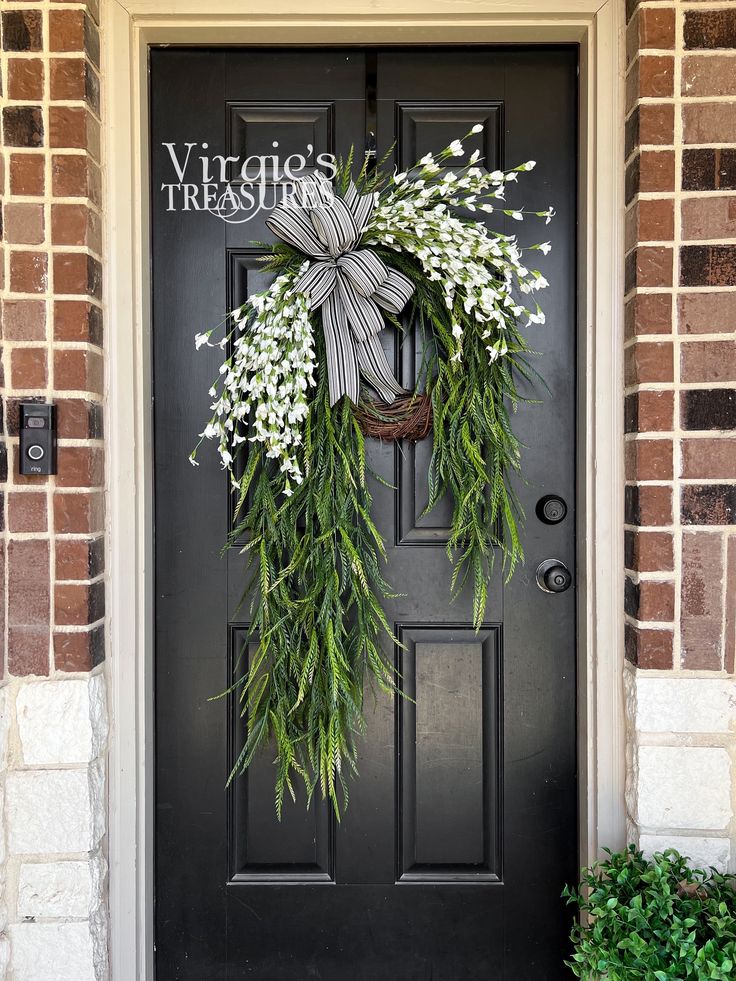 Blossom your surroundings with beautiful blooms. This wreath features foam leaves and paper blooms sporting a solid white color with saw grass stems cascading around the grapevine wreath. Add this lovely wreath to create a unique, one-of-a-kind statement!    Details: Dimensions (Varies Upon Shaping): 35"x22" Plant Type: Flower Bush Material: Foam, Paper & Plastic Color: White & Green Care & Safety: Indoor Use Only Quantity: 1 It is recommended that you keep your wreath under a well covered patio Elegant Door Wreaths, Contemporary Wreaths For Front Door, Front Door Decor Plants, Asymmetrical Porch Decor, Wreath With Storm Door, Double Wreath Ideas, Modern Front Door Wreath, Modern Door Wreath, Outside Home Decor