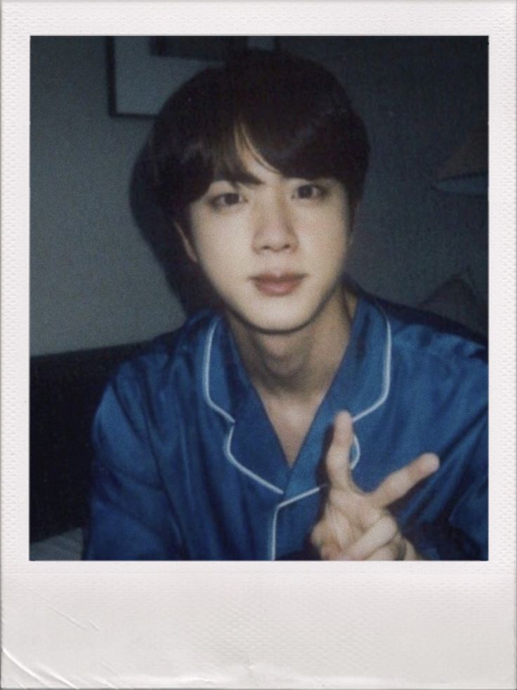 a young man is making the peace sign with his hand while sitting in front of a flower