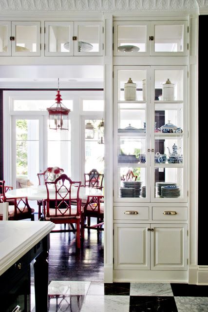 a kitchen with black and white checkered flooring, china cabinet, and dining room table