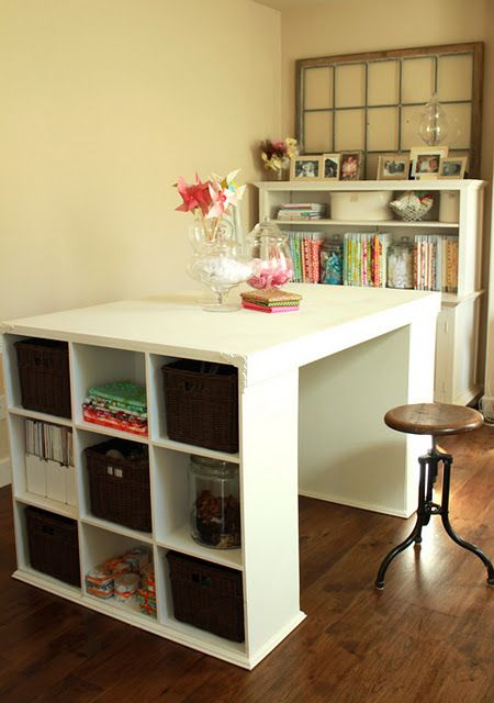 a white desk with baskets on it in front of a bookshelf filled with books