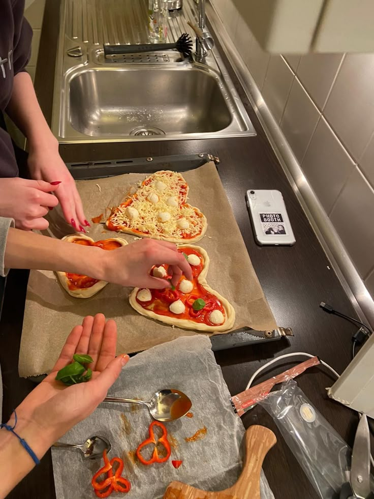 two women are making pizzas in the kitchen with utensils and spoons