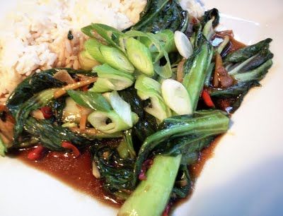 a white plate topped with rice and veggies next to broccoli covered in sauce