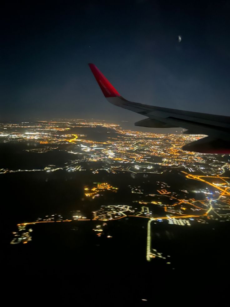 an airplane wing flying over the city lights at night