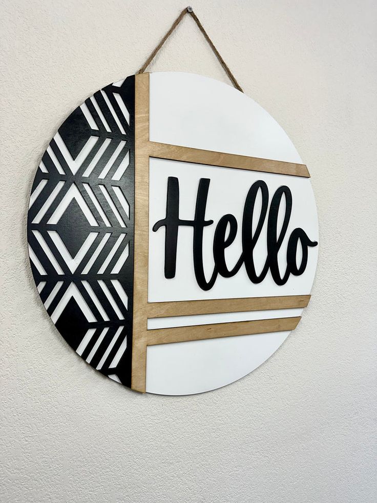 a sign hanging on the wall that says hello written in black and white letters,