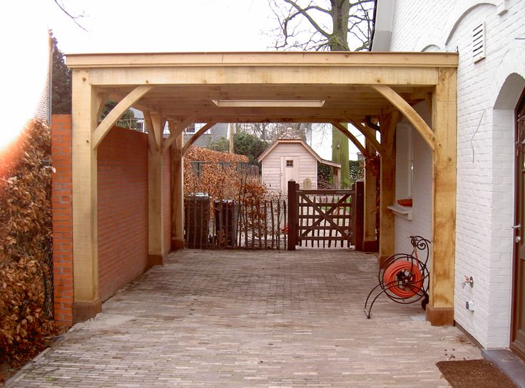 an outdoor covered patio with brick pavers and wood fenced in area next to the house