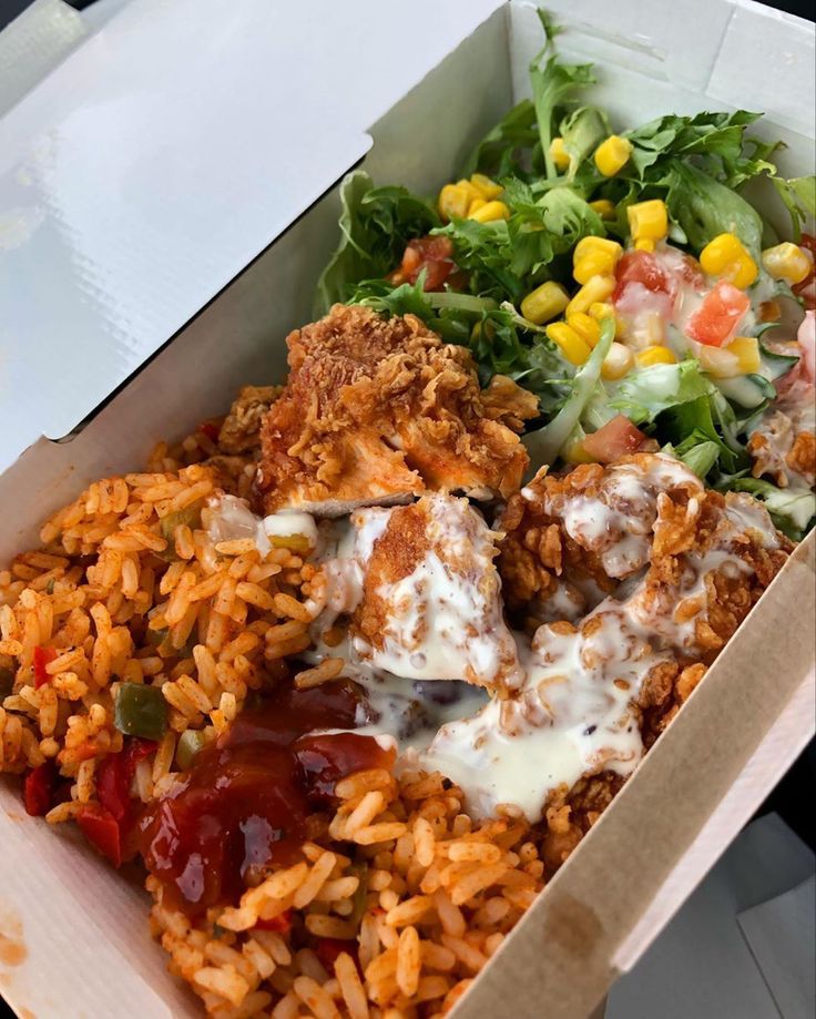 a box filled with lots of food next to a salad