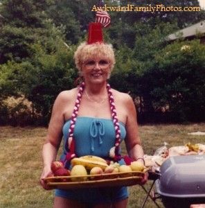 a woman holding a tray full of fruit in front of a bbq with an american flag on it