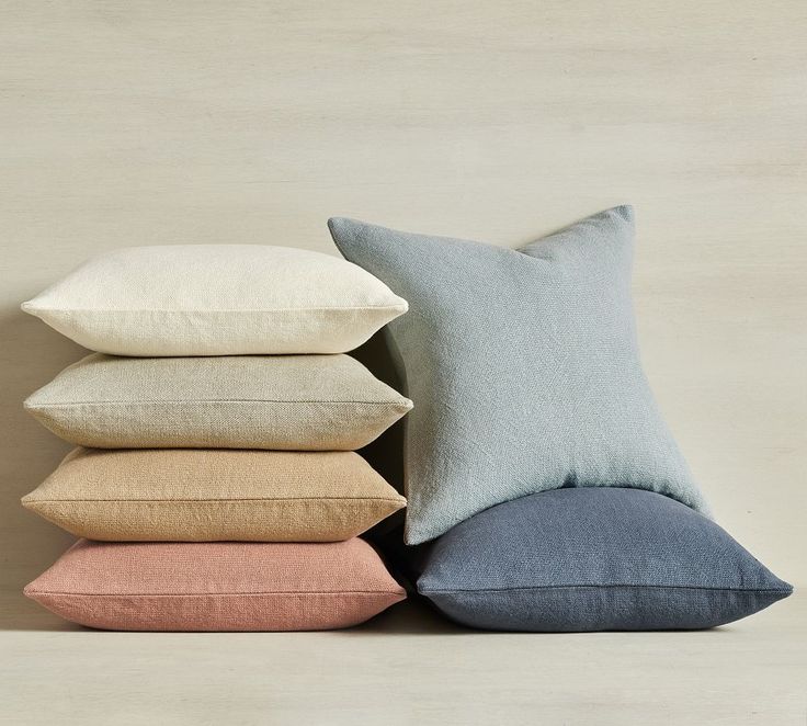 four pillows stacked on top of each other in different colors and sizes, with the same pillow