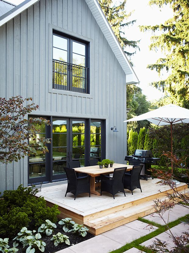 an outdoor patio with table and chairs next to the house's front door, surrounded by trees