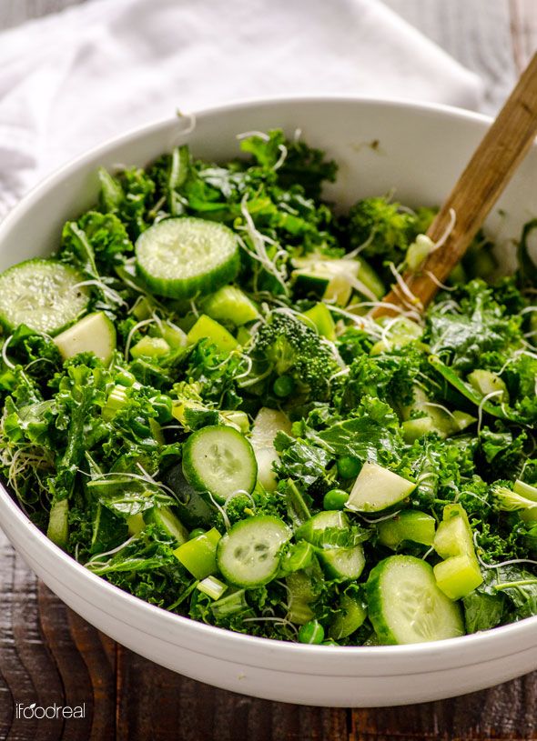 a white bowl filled with green vegetables on top of a wooden table