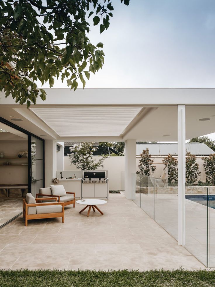 an outdoor living area with chairs, table and grill