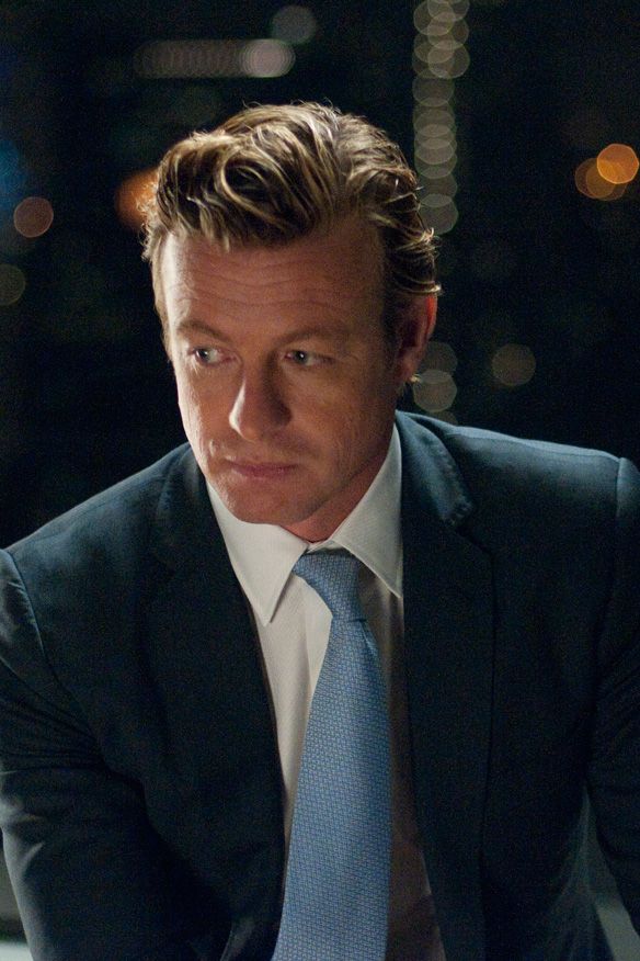 a man in a suit and tie sitting down at a table with his hands on his knees