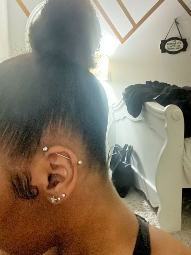 a close up of a person with ear piercings on their ears and hair in a bun