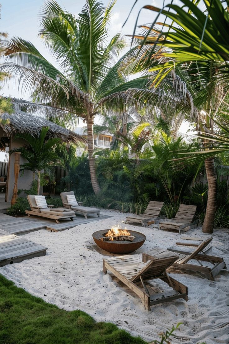 a fire pit sitting on top of a sandy beach next to trees and lawn chairs