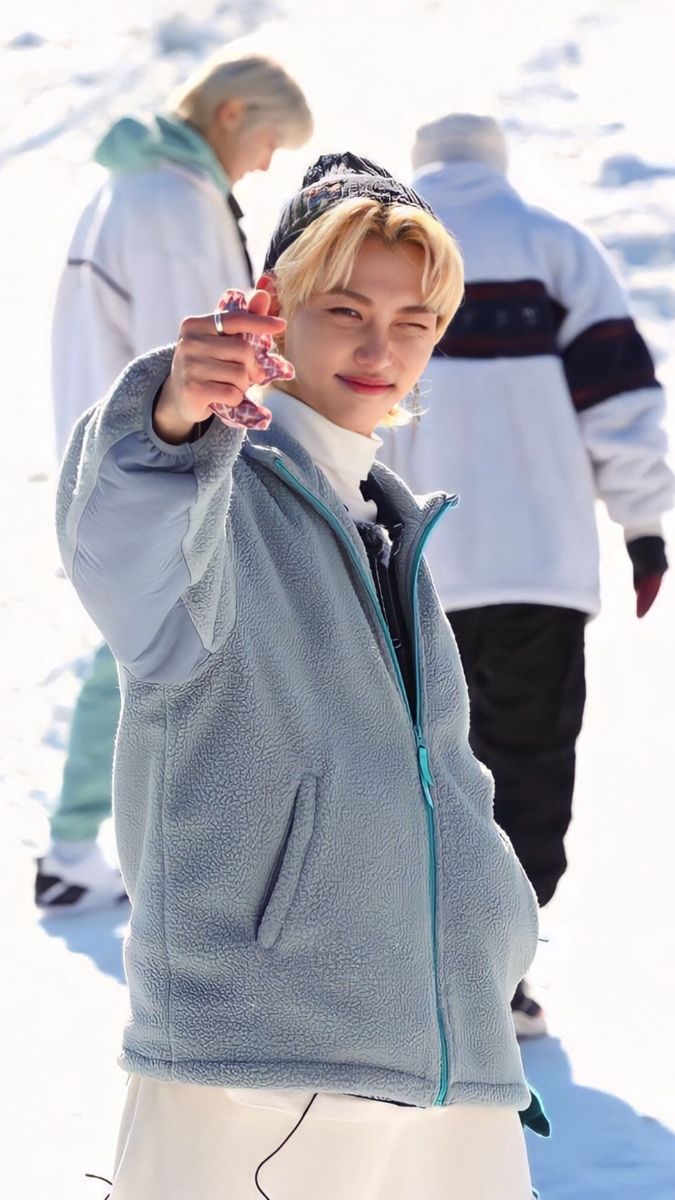 the young man is pointing at something while standing in the snow with other people behind him