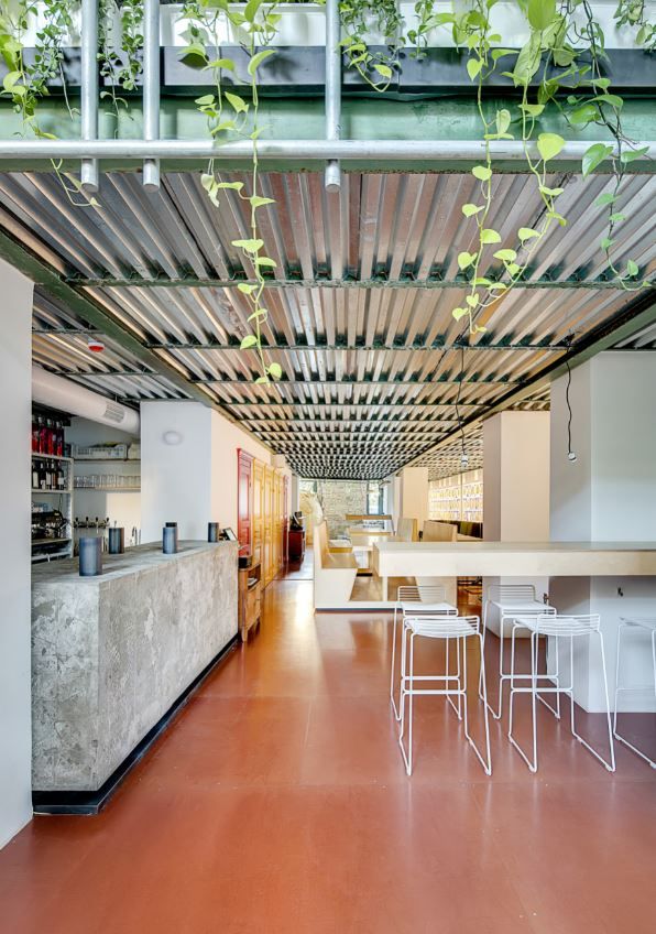 the interior of a modern restaurant with white tables and stools under a metal roof