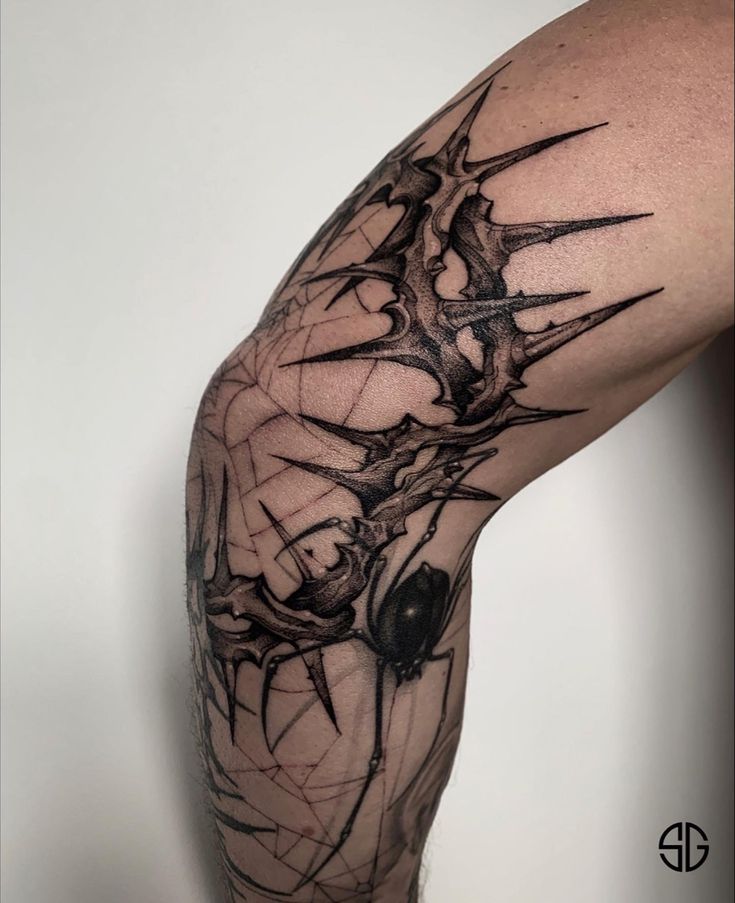 a man's leg with tattoos on it and an image of a spider in the middle