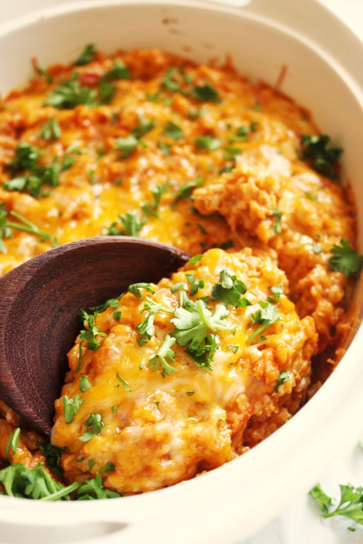 a white casserole dish with meat and cheese in it, topped with parsley