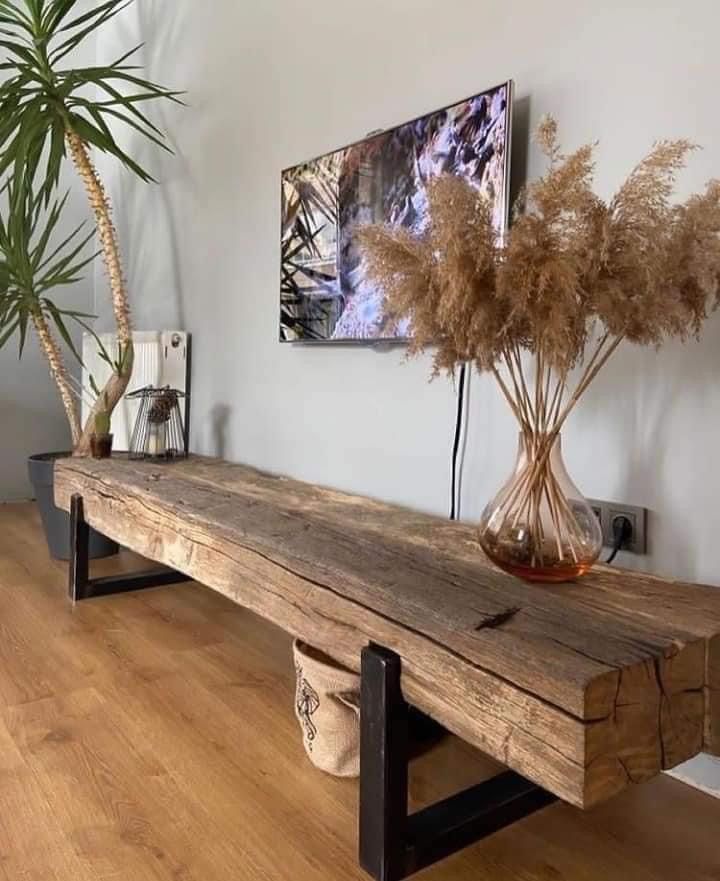 a wooden bench sitting next to a potted plant on top of a hard wood floor