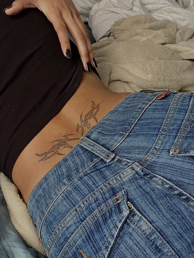 a woman laying on top of a bed with her stomach covered in blue jean shorts