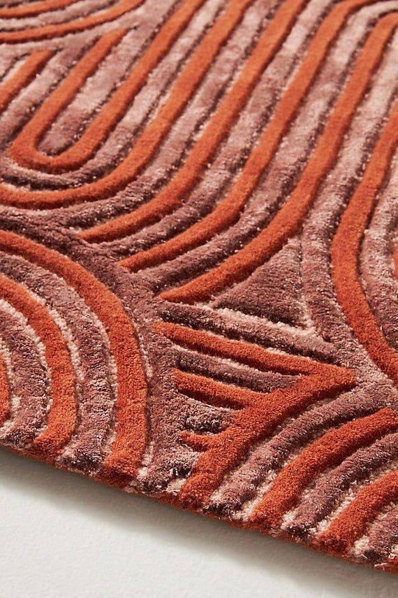 an orange and brown area rug on top of a white table