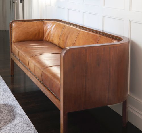 a brown leather couch sitting in front of a mirror on the side of a wall