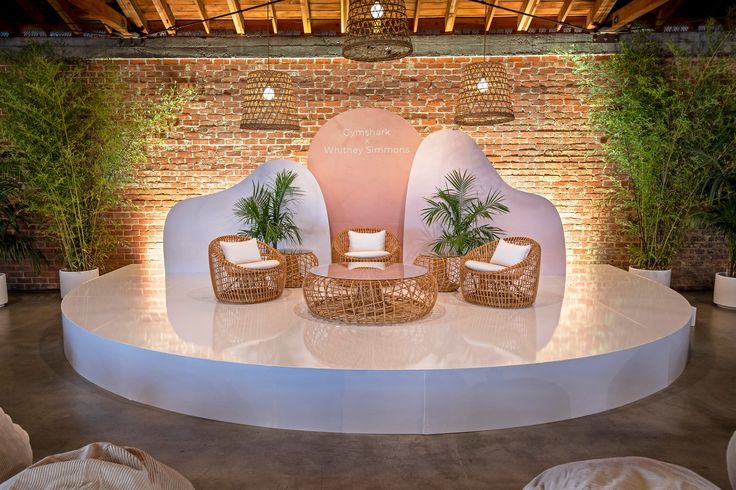 an outdoor stage with wicker furniture and potted plants on the top floor, surrounded by greenery