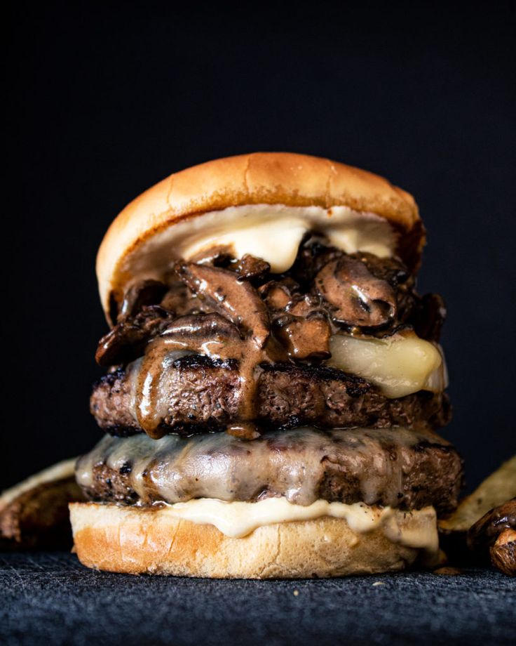 two hamburgers stacked on top of each other with meat and cheese in between them