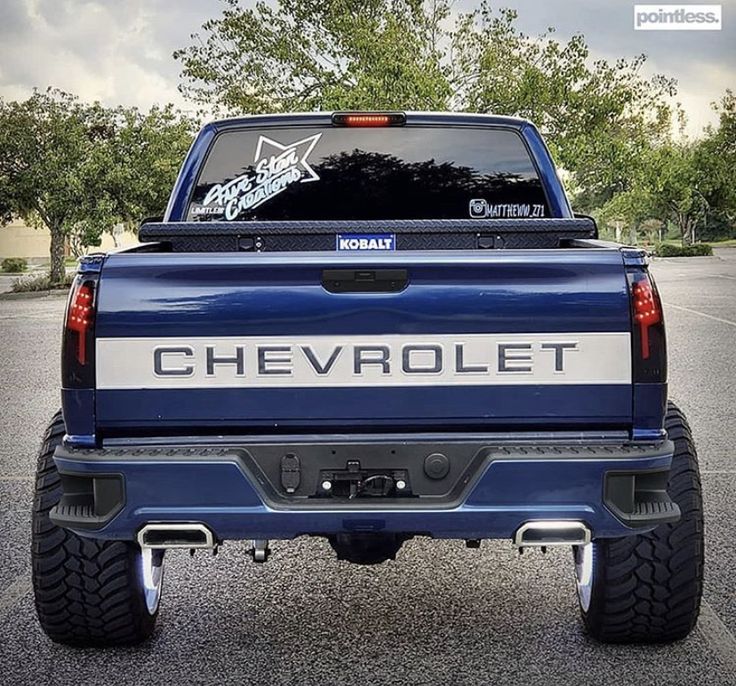 the back end of a blue chevrolet truck parked in a parking lot