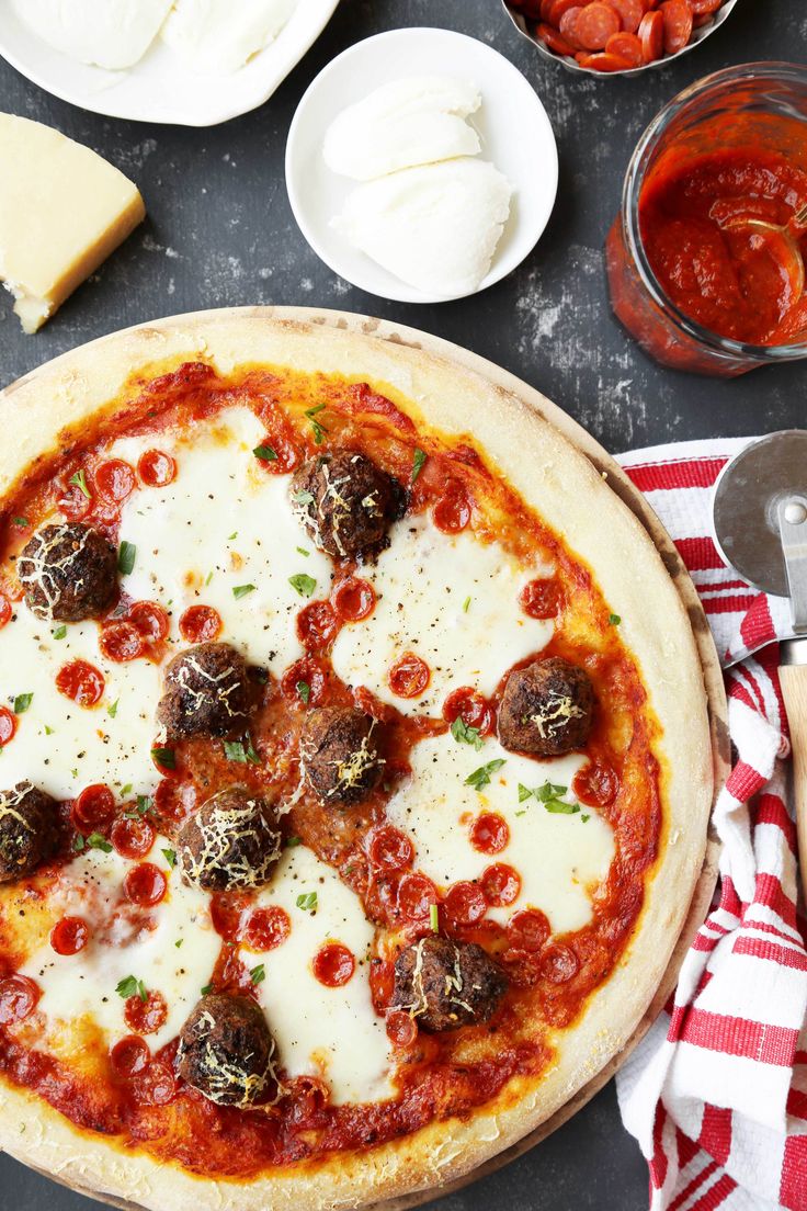 a pizza sitting on top of a pan covered in cheese and toppings next to other dishes