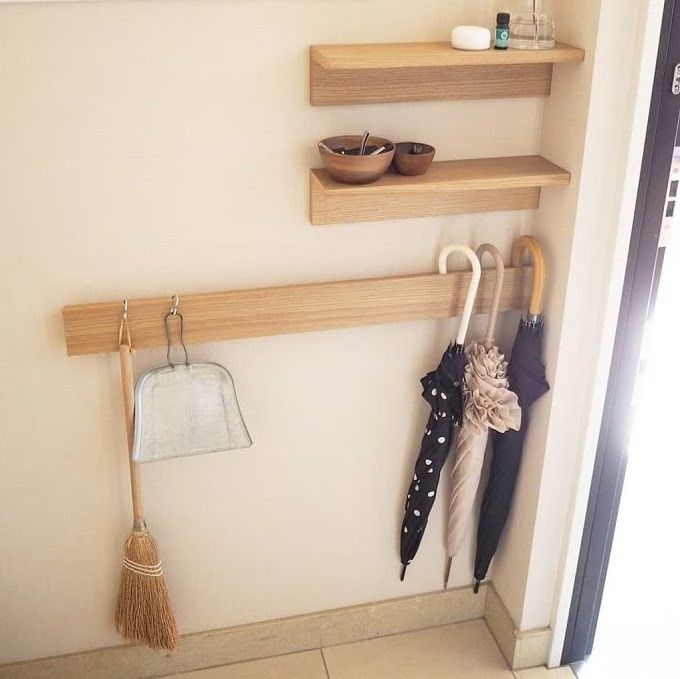 two wooden shelves with umbrellas and hats hanging on them, in front of a window