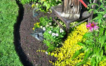 a birdhouse sitting on top of a wooden bench in the middle of a garden