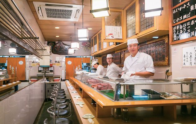 two chefs preparing food in a kitchen with lots of counter space and wood paneling