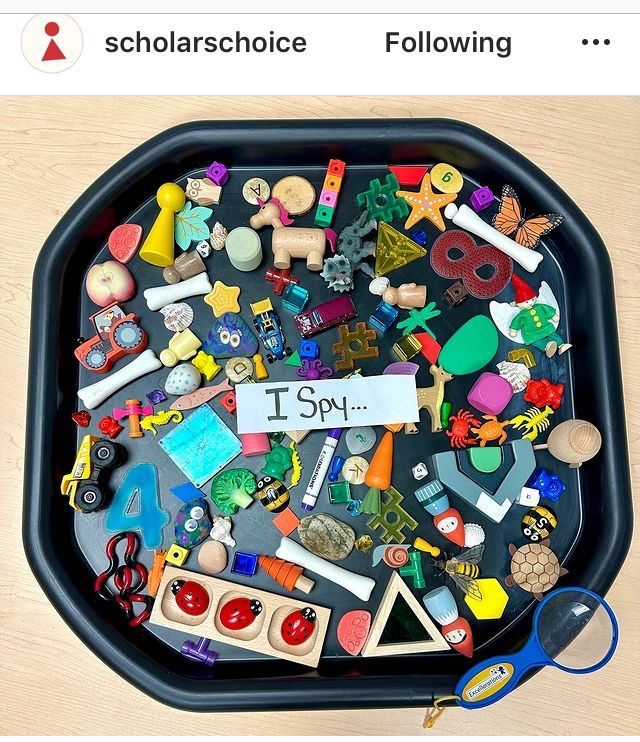 a black tray filled with lots of different types of toys on top of a wooden table