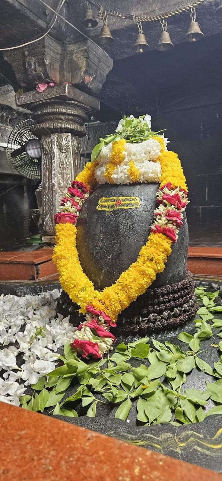 a statue with flowers around it on the ground