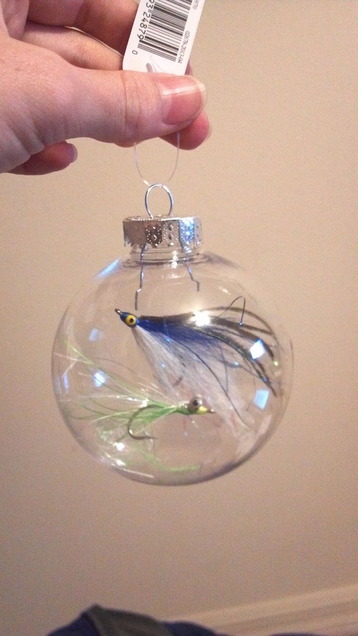 a hand holding a glass ornament with a fish in it