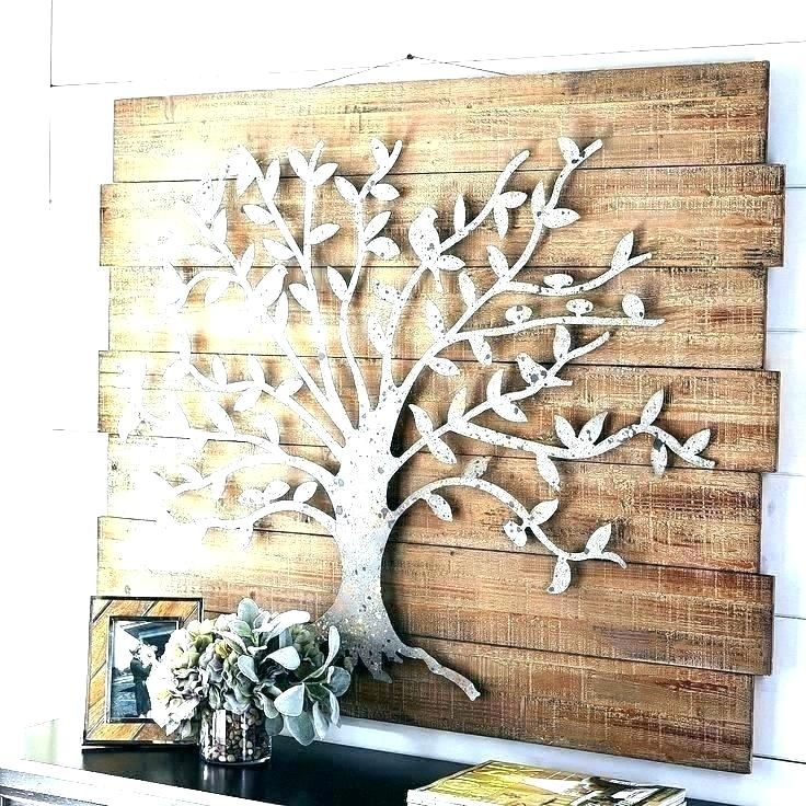 a white tree is mounted on a wooden wall next to a vase with flowers in it